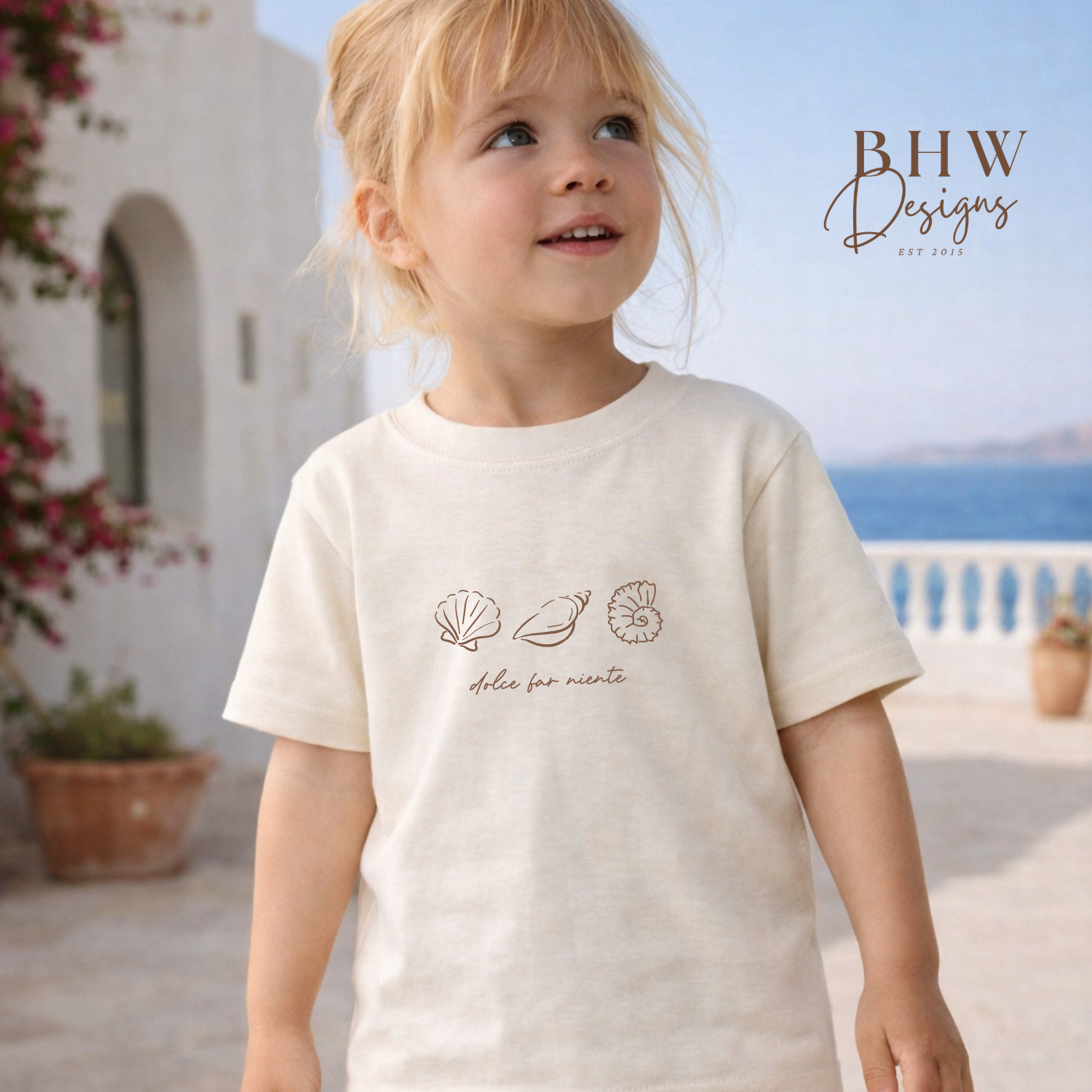 Child wearing a white t-shirt with shell designs outdoors