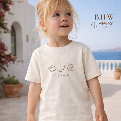 Child wearing a white t-shirt with shell designs outdoors