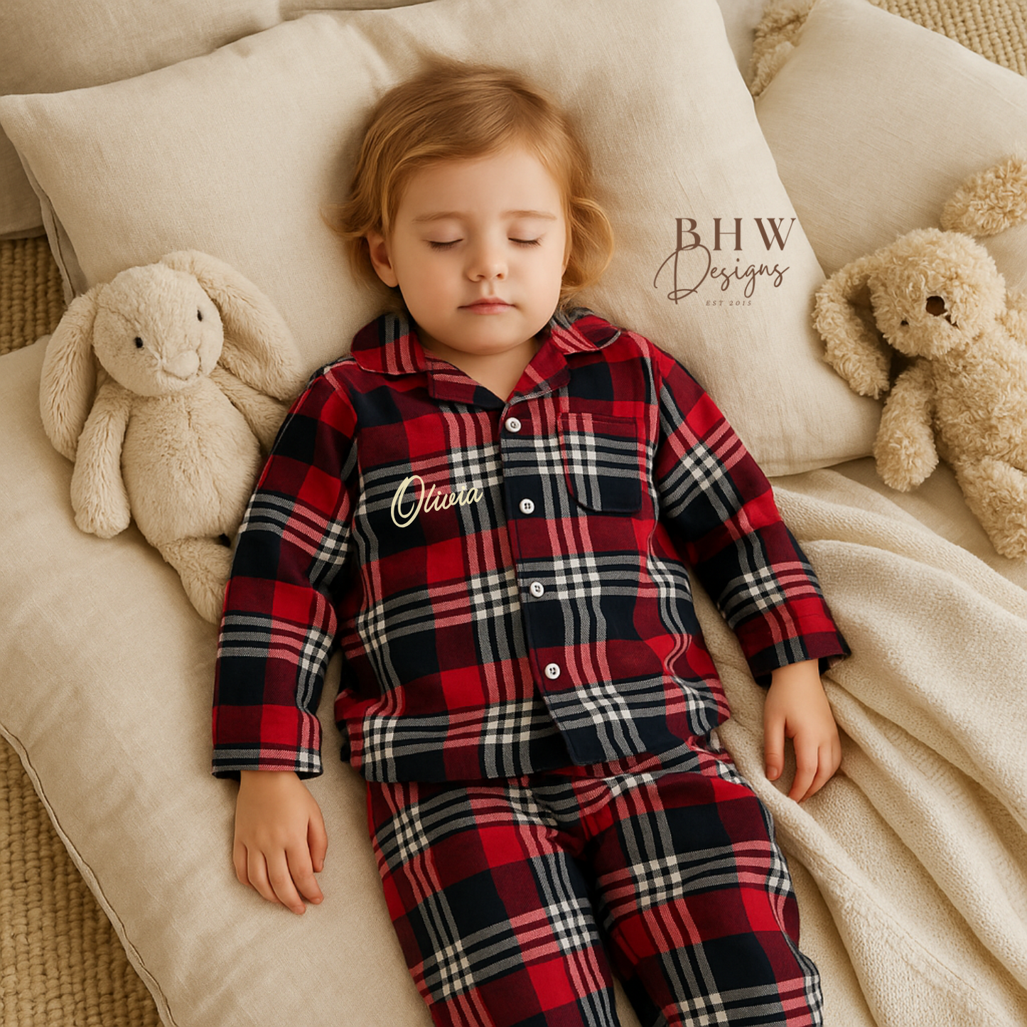 Child asleep wearing a red, navy and white plaid pyjamas personalised with name on the front. 