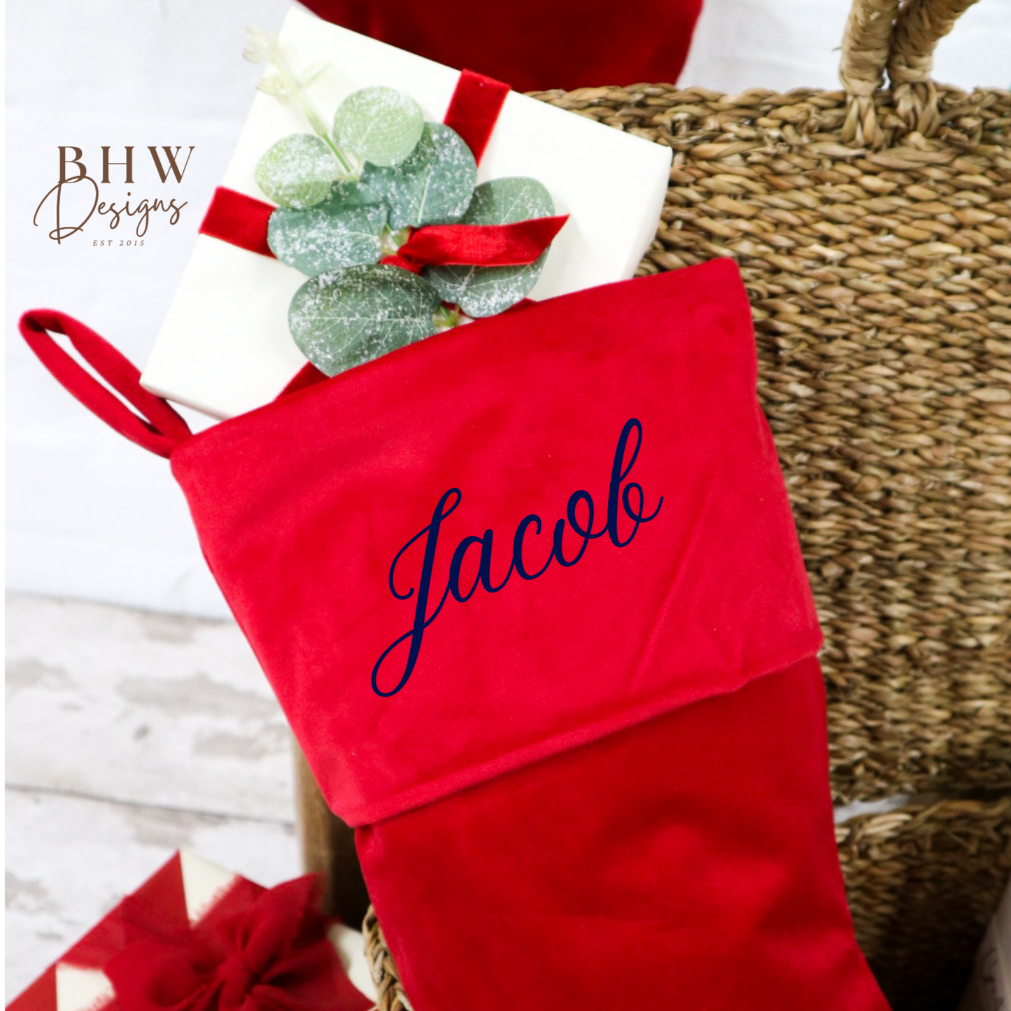 Red Christmas stocking with 'Jacob' personalised on it, placed on a woven basket.