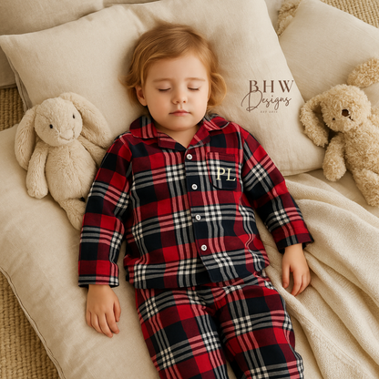 Child wearing a red and blue plaid pyjama set with 'PL' initials. 
