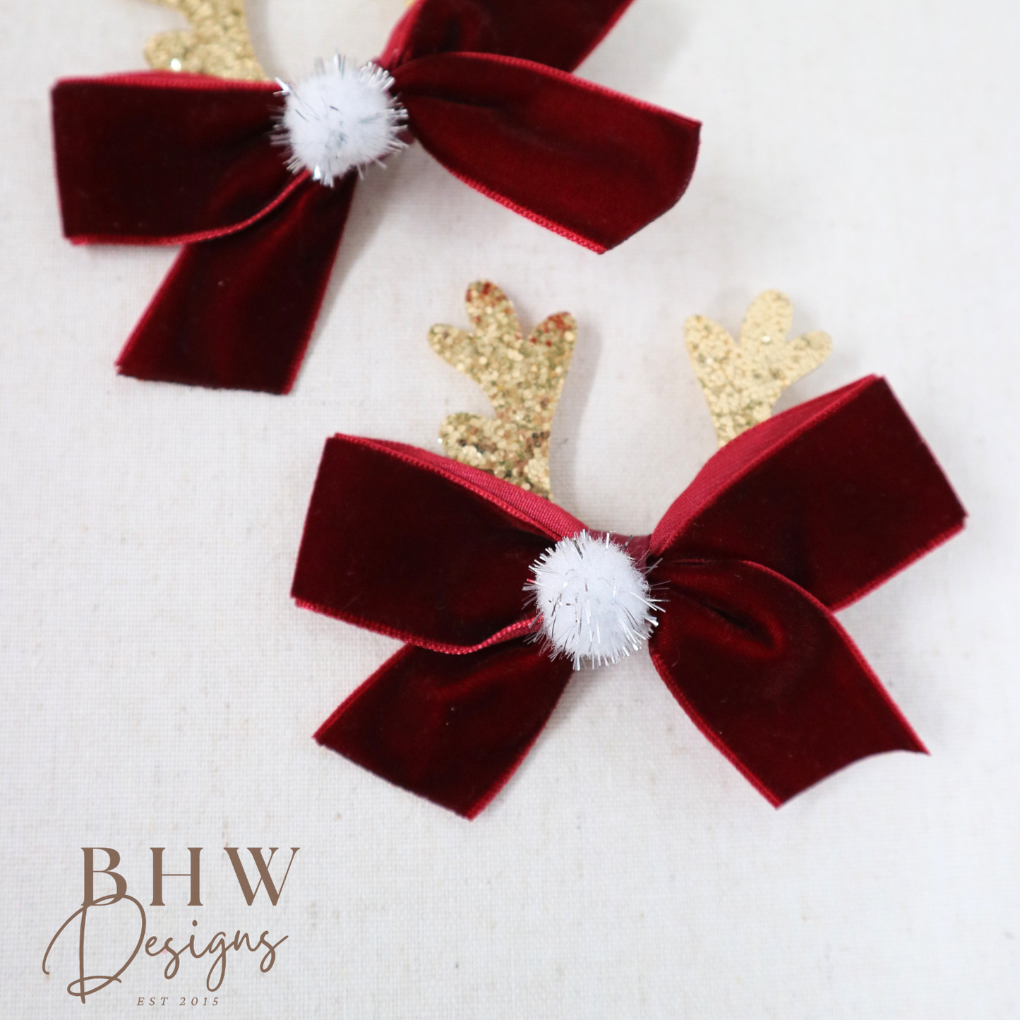 Red velvet bows with gold reindeer antlers and white pom-poms