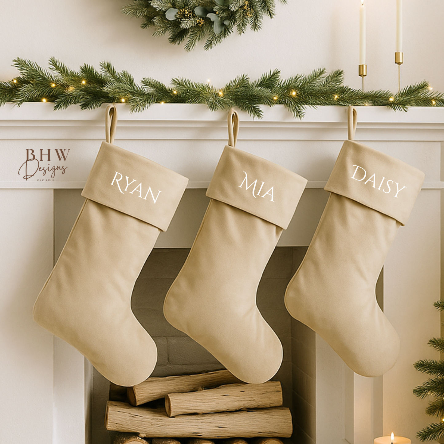Three beige stockings hanging on a fireplace mantle with personalised names, decorated with a wreath and candles.