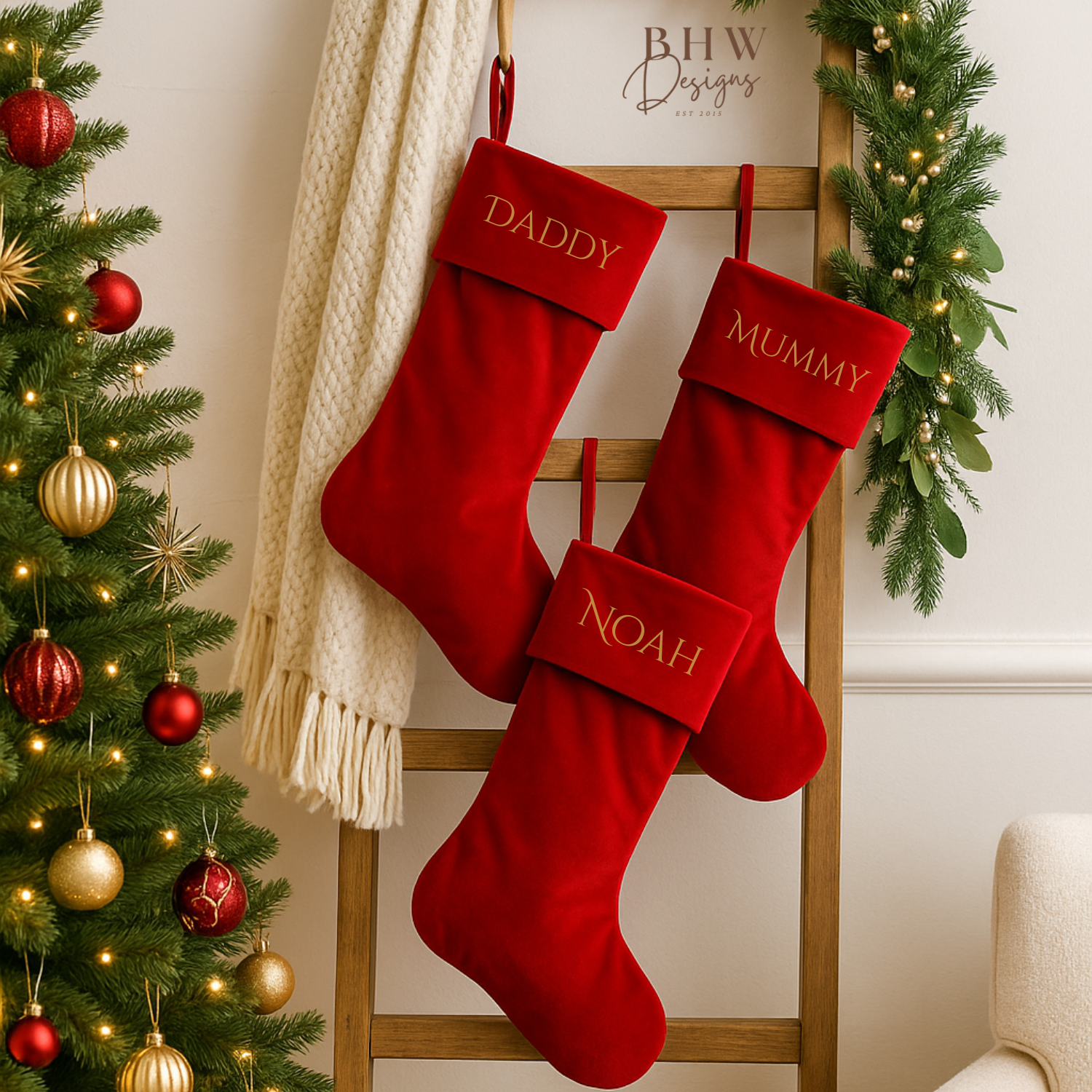 Red Christmas stockings with personalised names on a wooden ladder next to a decorated tree.
