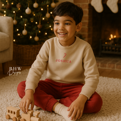 Child wearing a oat colour sweatshirt with a red candy cane and Joshua personalised on it 