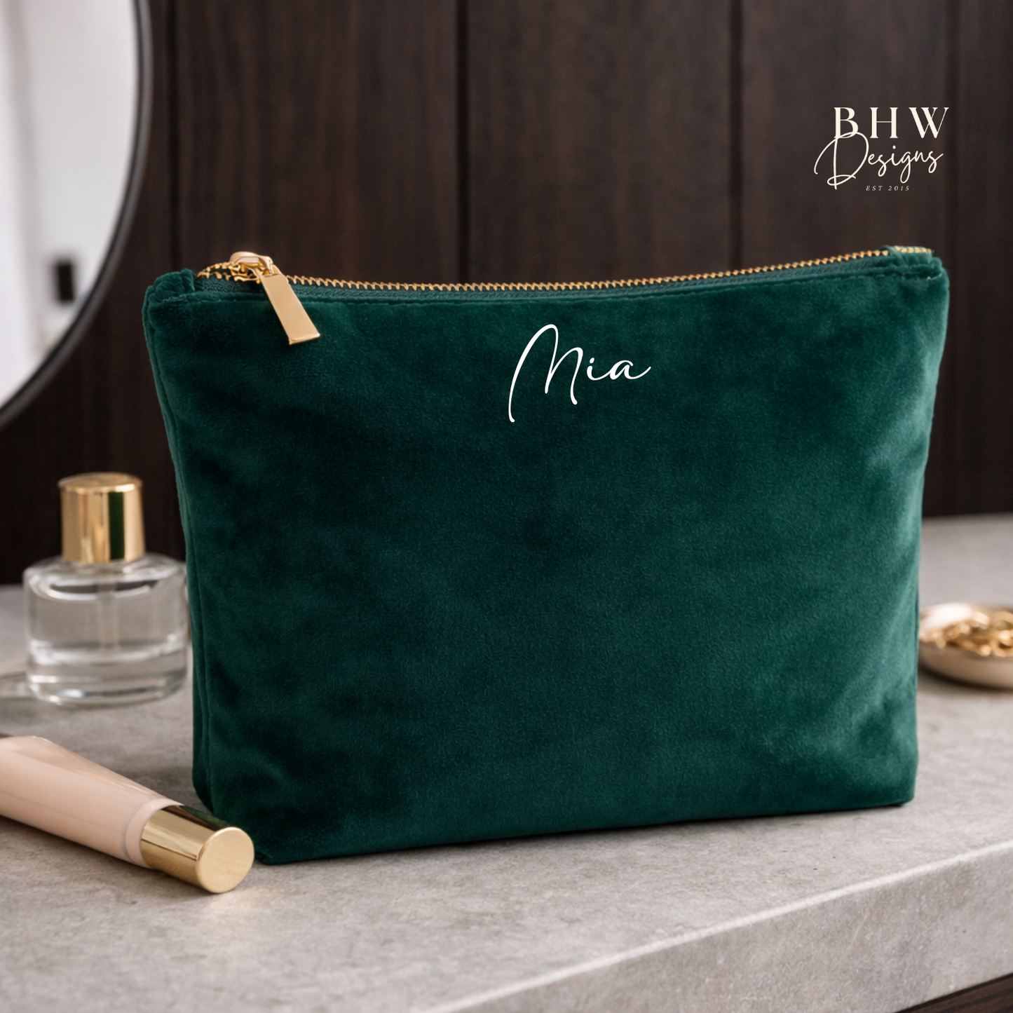 Green velvet pouch with 'Mia' monogram on a bathroom counter, branded 'BHW Designs'.