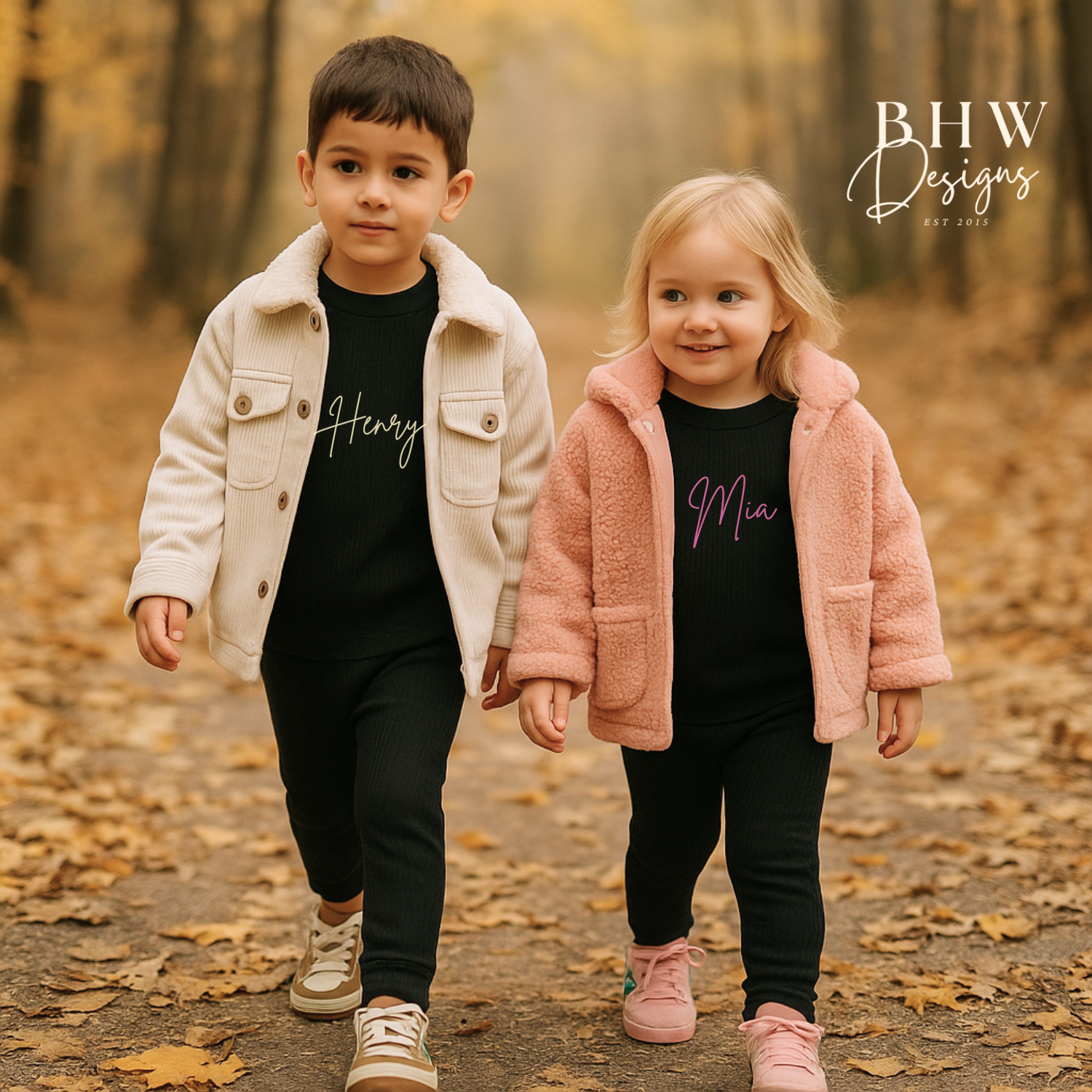 Two children wearing ribbed black loungewear personalised with names, walking in a forest 