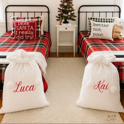Children's bedroom with two beds, with two white Santa sacks with white faux fur trim and pom pom's with Luca and Kai on the front in red