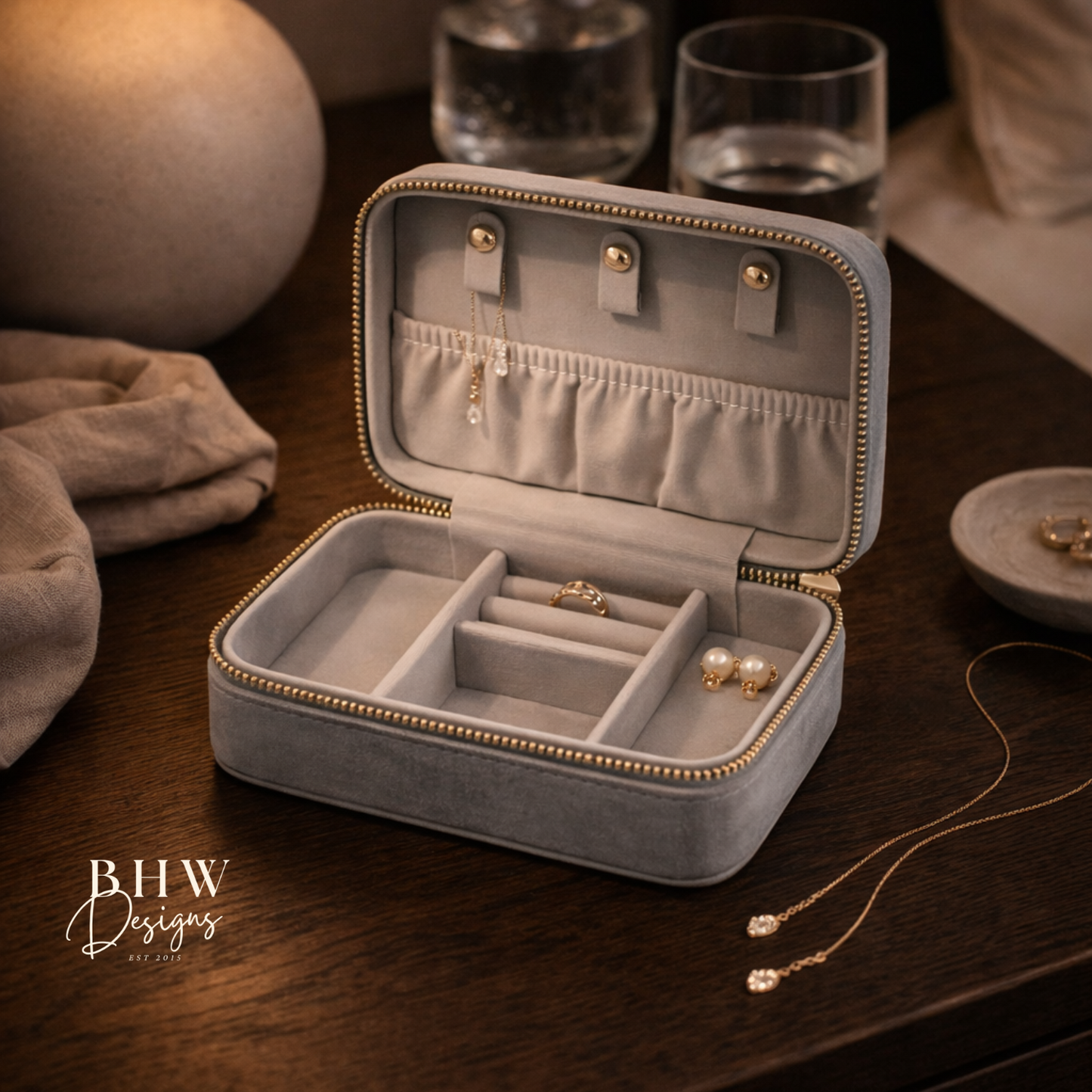 Grey jewellery box with gold accents on a wooden surface, 