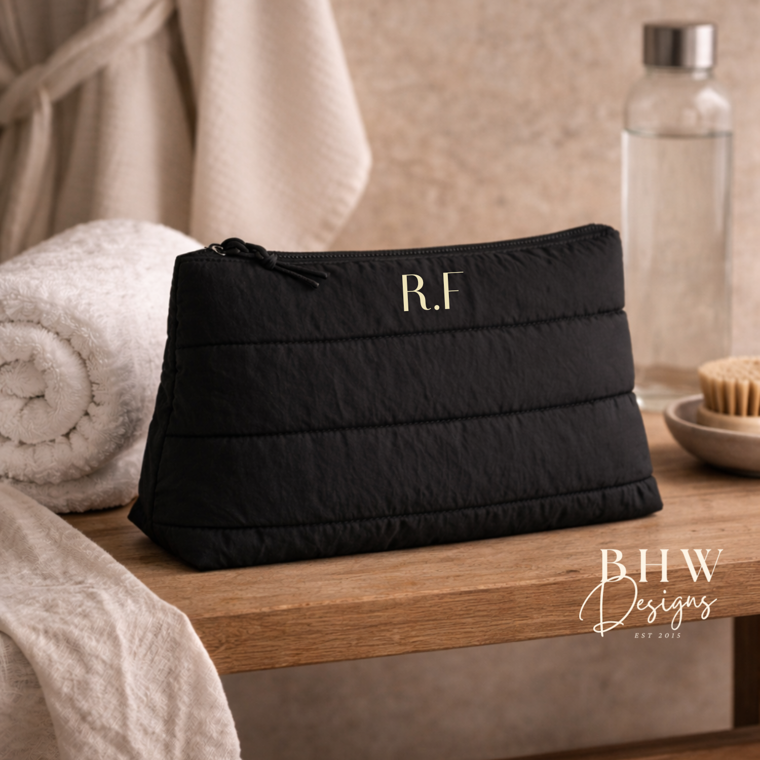 Black quilted pouch with 'RF' initials on a wooden surface, 
