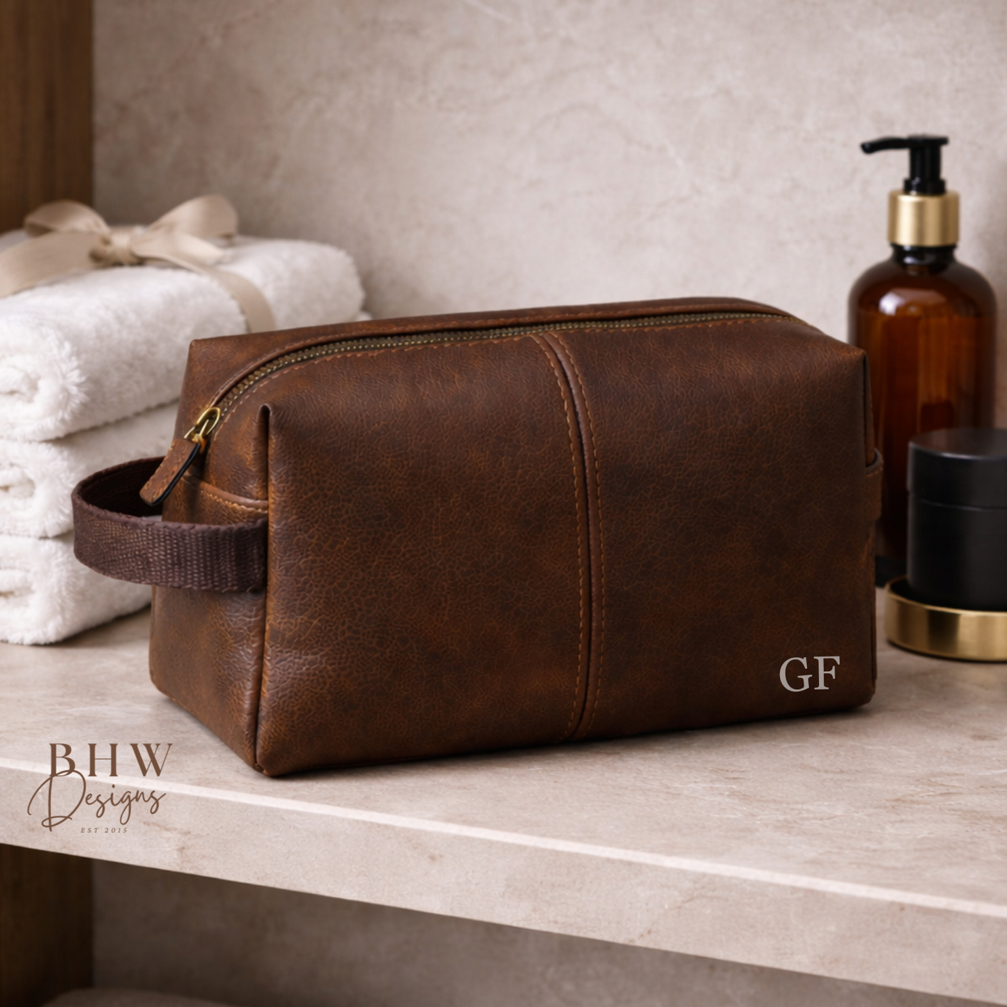 Brown faux leather toiletry bag on a bathroom counter with towels and bottles in the background.
