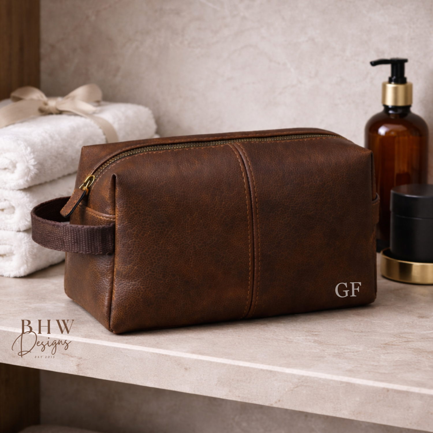 Brown faux leather toiletry bag on a bathroom counter with towels and bottles in the background.