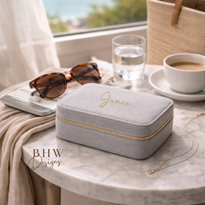 Grey velvet jewellery box with 'Grace' on in gold a marble table with sunglasses, water, and coffee.