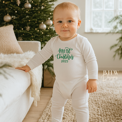 Baby wearing a onesie with 'My 1st Christmas 2025' text in a festive indoor setting.