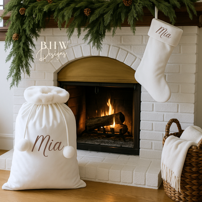White stockings and sack with 'Mia' printed on them in front of a fireplace.