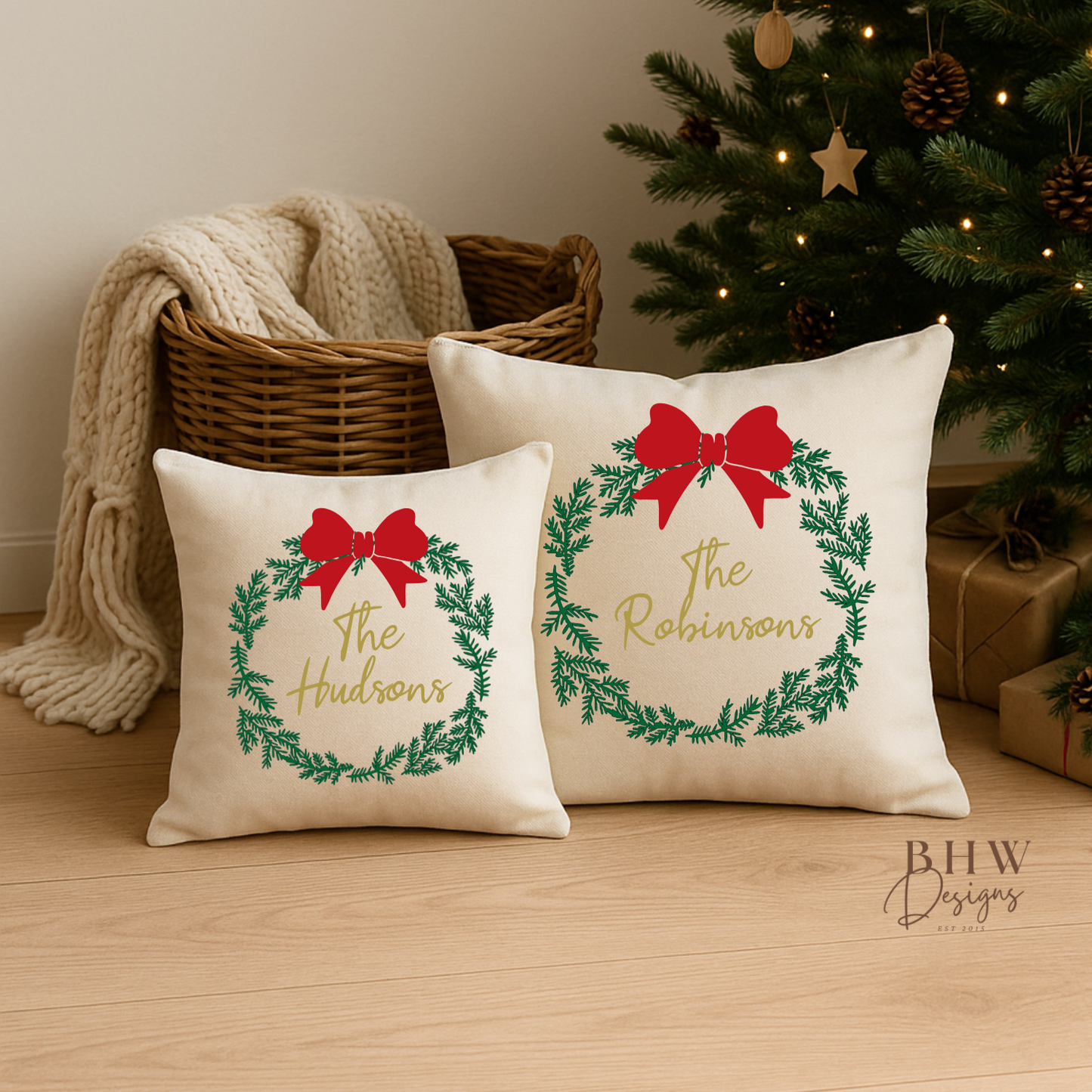 Two decorative personalised wreath and bow design cushion covers in front of a decorated tree.