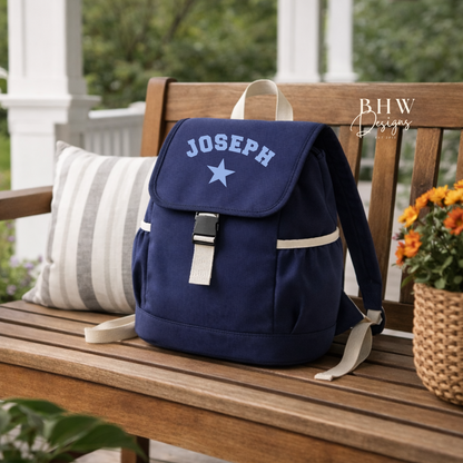 Navy blue backpack with 'JOSEPH' and a star on a wooden bench outdoors.