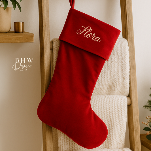 Red Christmas stocking with 'Flora' personalised hanging on a wooden ladder.