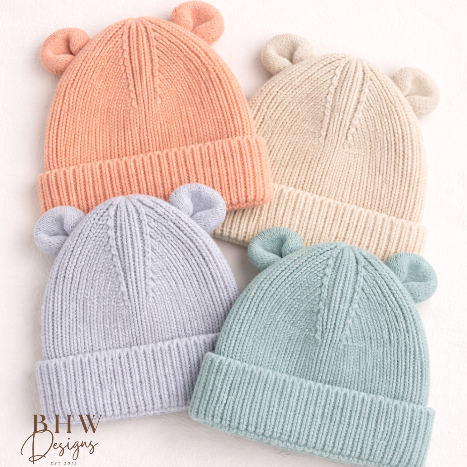 Four knitted baby hats in peach, sand, cloudy grey and dusky turquoise. 