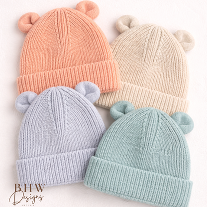 Four knitted baby hats in peach, sand, cloudy grey and dusky turquoise. 