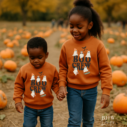 Two children wearing matching 'Boo Crew' sweatshirts in a pumpkin patch.