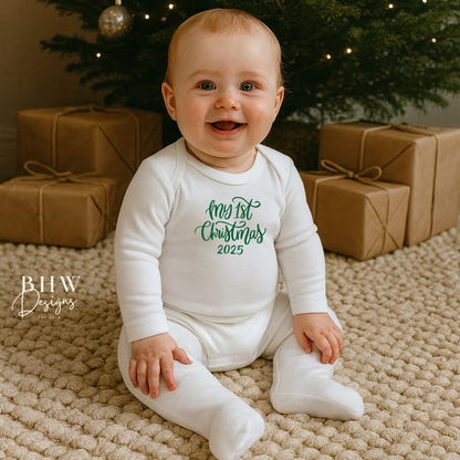 Baby wearing a 'My 1st Christmas 2025' onesie in front of a decorated Christmas tree with presents.