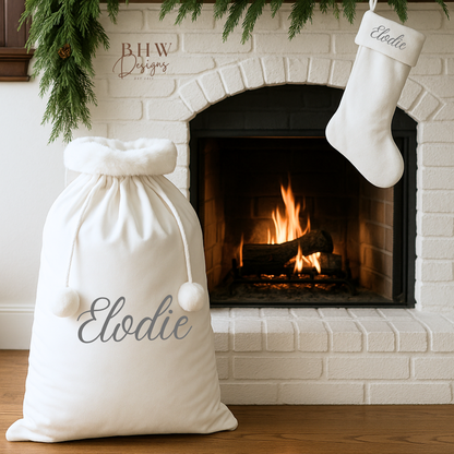 White personalised santa sack and stocking in front of a fireplace.