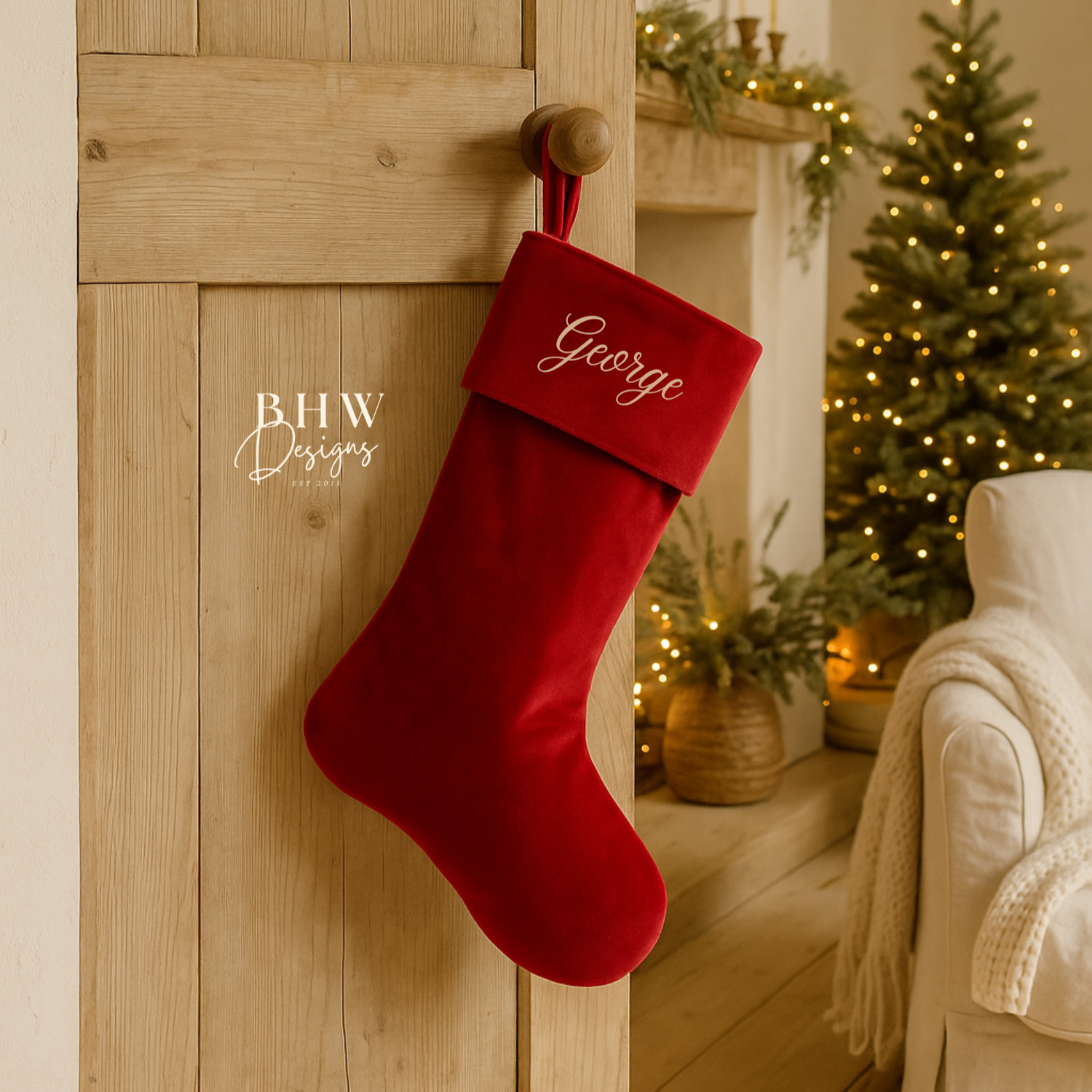Red Christmas stocking with 'George' personalised on it, hanging on a wooden door with a decorated tree in the background.