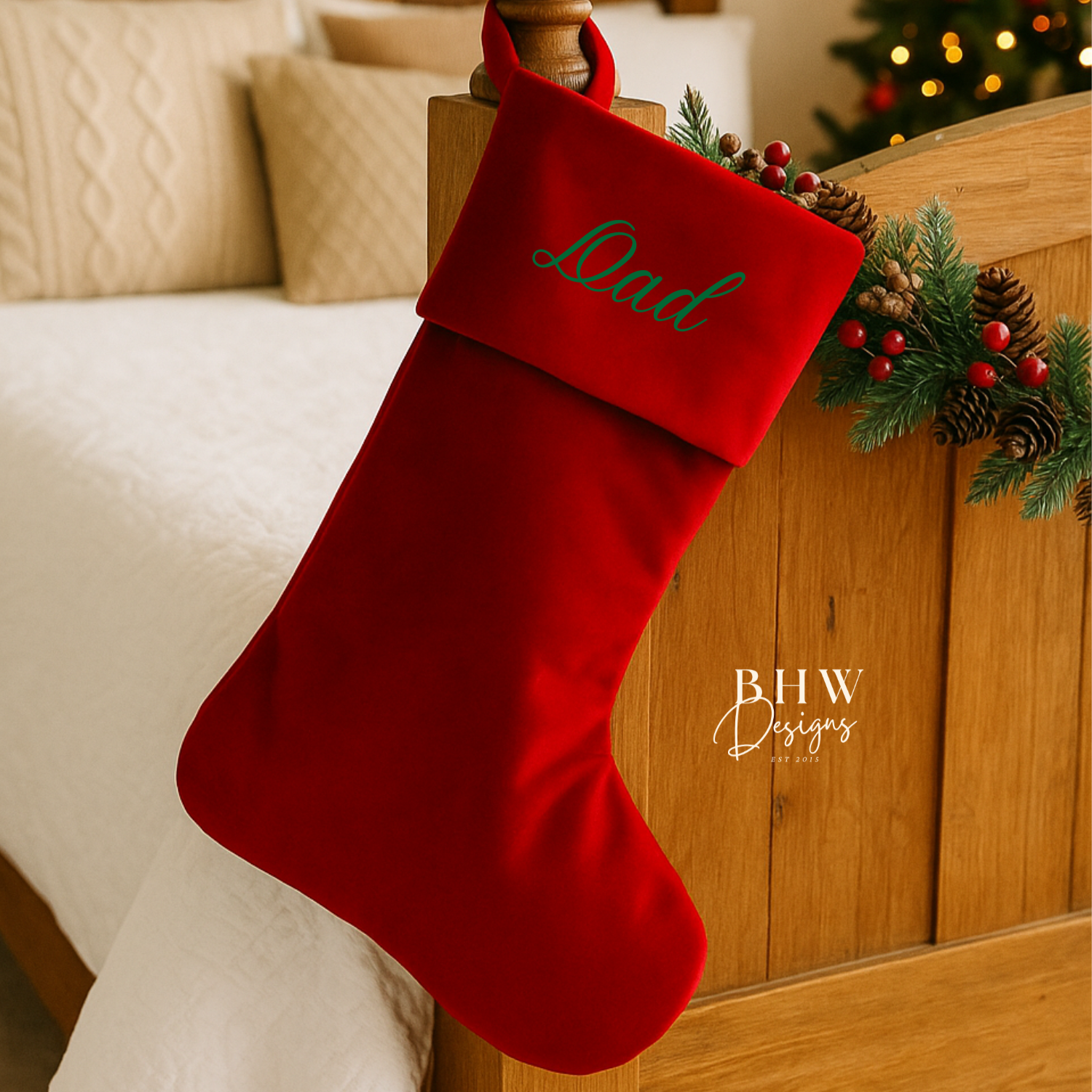 Red Christmas stocking with 'Dad' personalised on a wooden bed, decorated with greenery and berries.