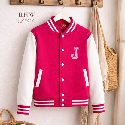 Pink varsity jacket with white sleeves hanging on a wooden hook rack.