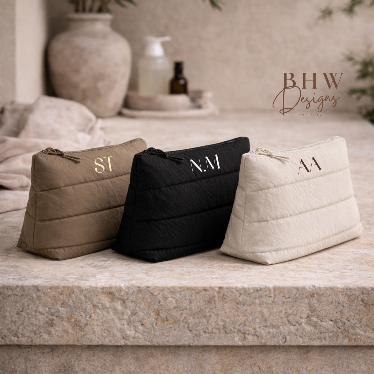 Three monogrammed bags on a stone surface