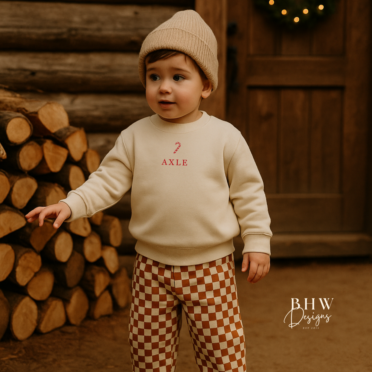 Child wearing a oat colour sweatshirt with a candy cane an Axle on the front in red