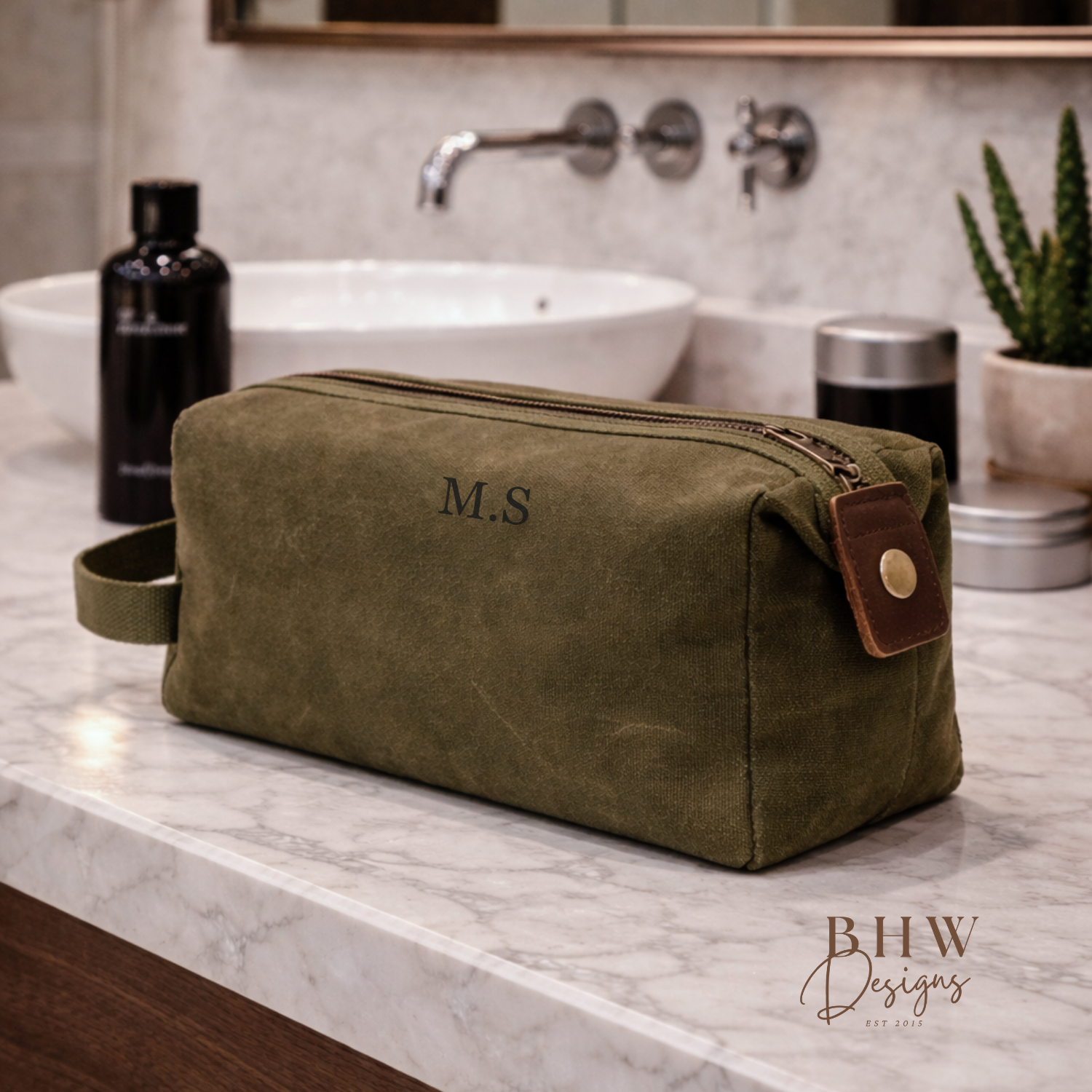 Green toiletry bag with initials on a bathroom counter, featuring 'BHW Designs'.