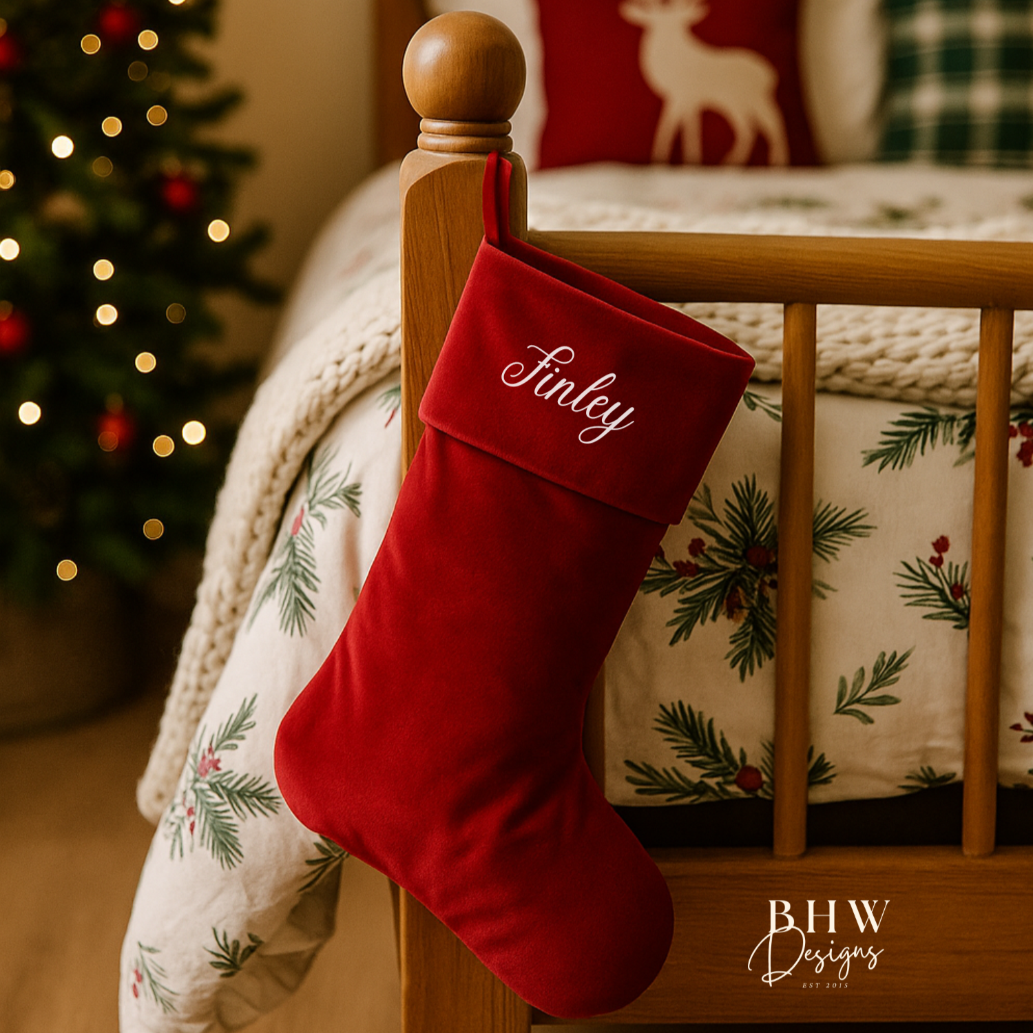 Red Christmas stocking with 'Finley' personalised on it, hanging on a wooden bed post with a decorated tree in the background.