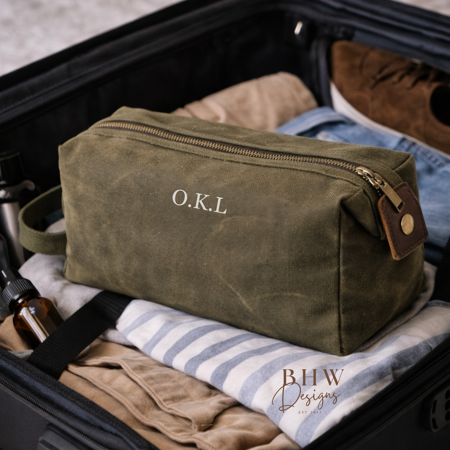 Green toiletry bag with 'O.K.L.' initials in a suitcase with clothes