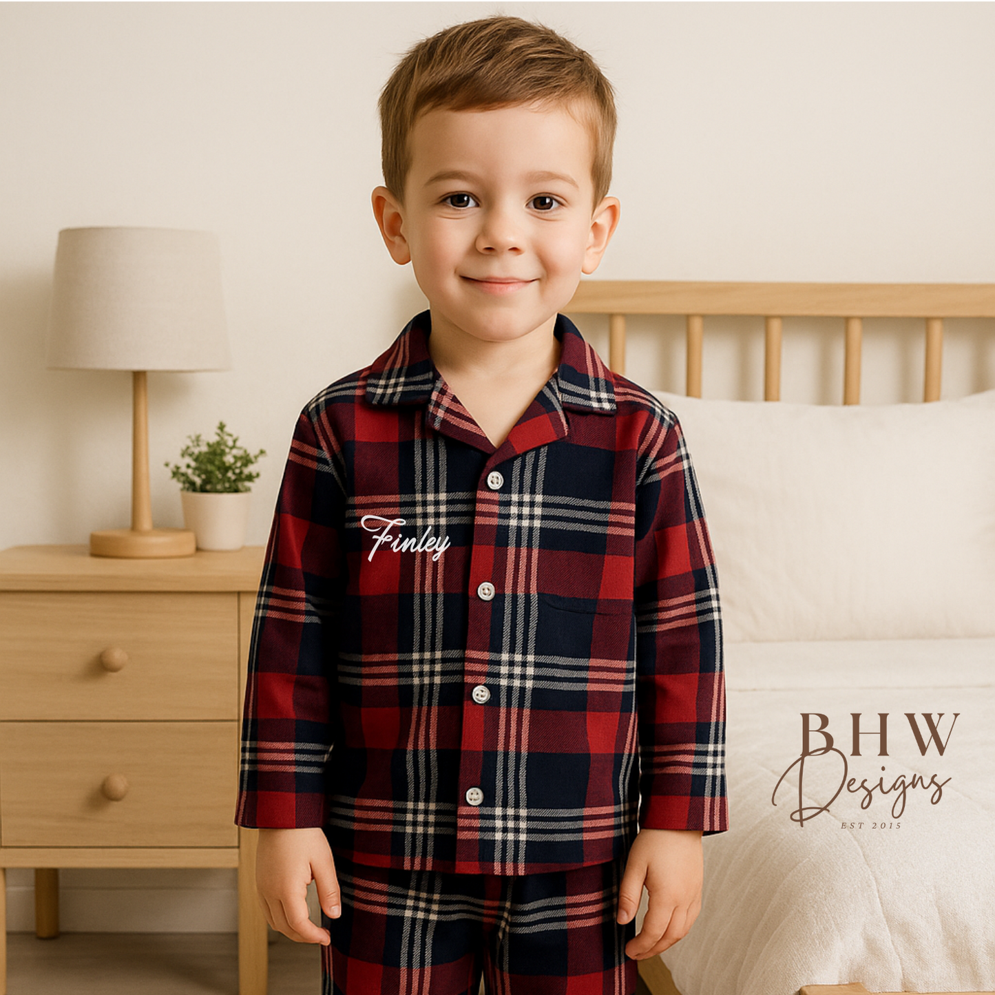 Child wearing a red, navy and white plaid pyjamas personalised with name on the front. 