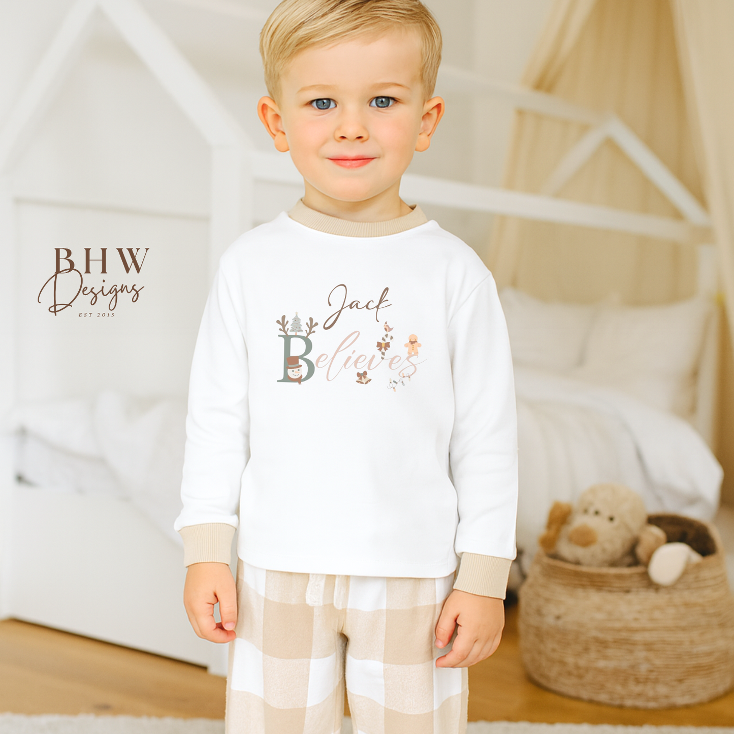 Child wearing a white long-sleeve top with beige cuffs personalised on the front with believes and beige and white check trousers
