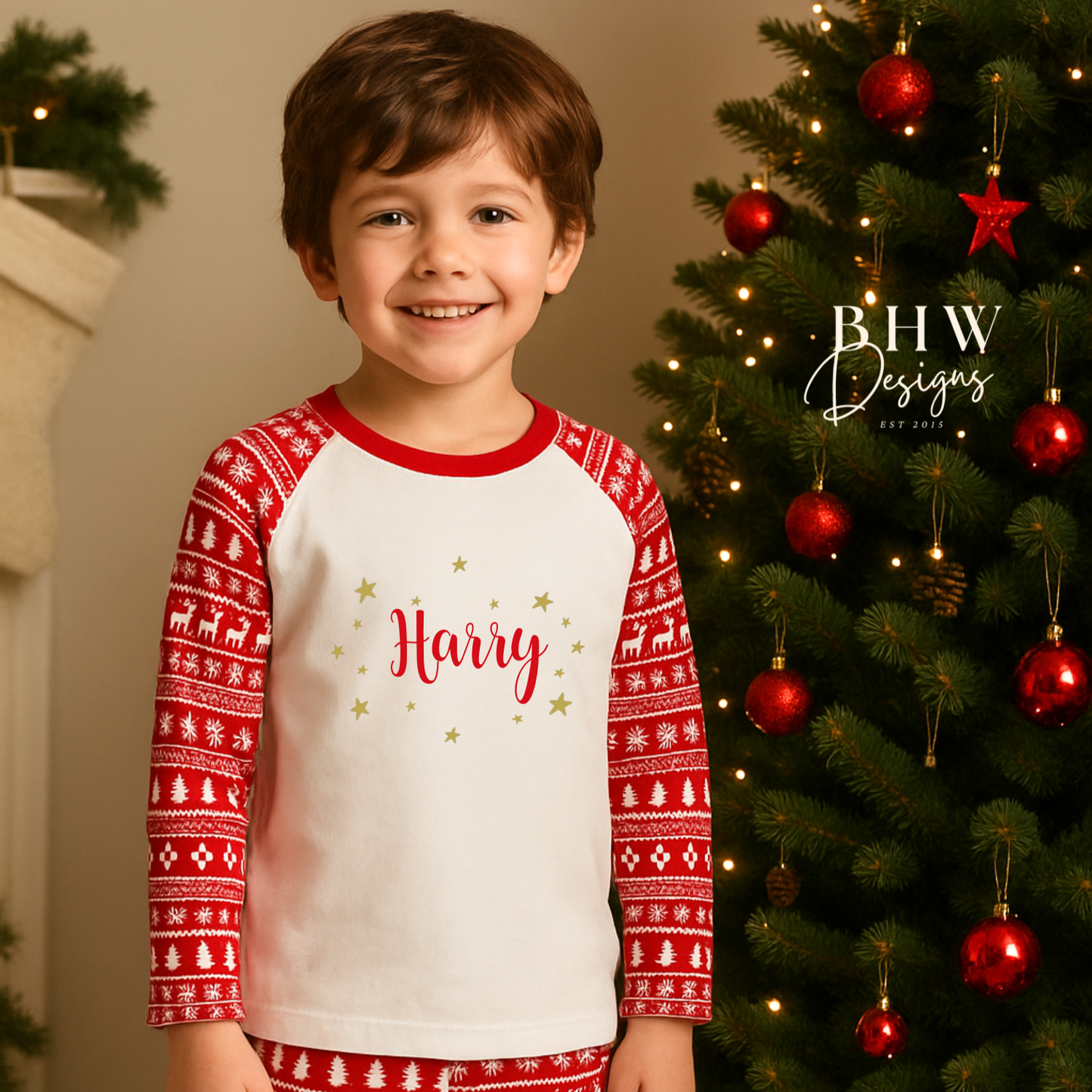 Boy wearing red and white fair isle print pyjamas with 'Harry' printed on them with gold stars. 