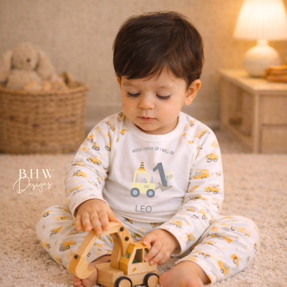 Child wearing personalised digger print pyjamas playing with a wooden toy in a cozy room setting