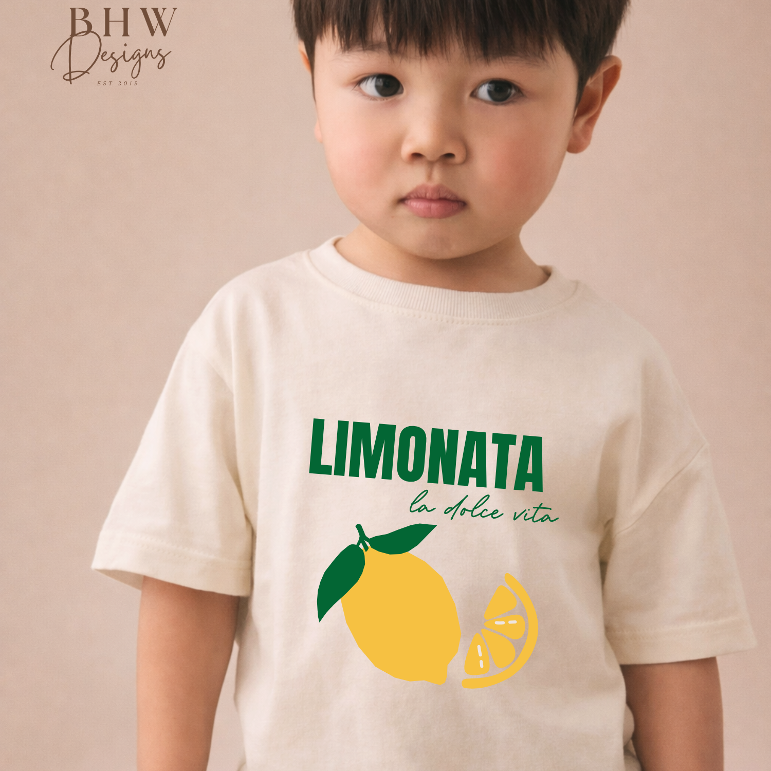 Child wearing a 'Limonata' t-shirt with a lemon graphic on a beige background