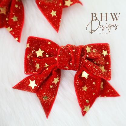 Red glittery bow with gold stars on a white background