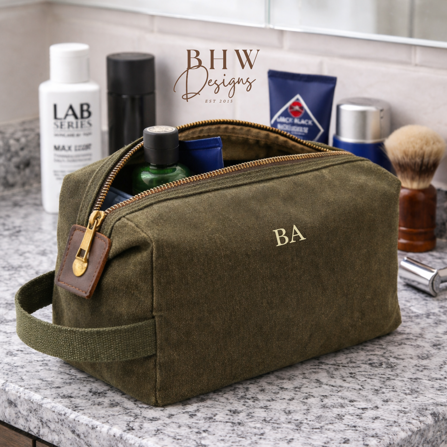 Olive green toiletry bag with 'BA' initials on a bathroom counter with grooming products.