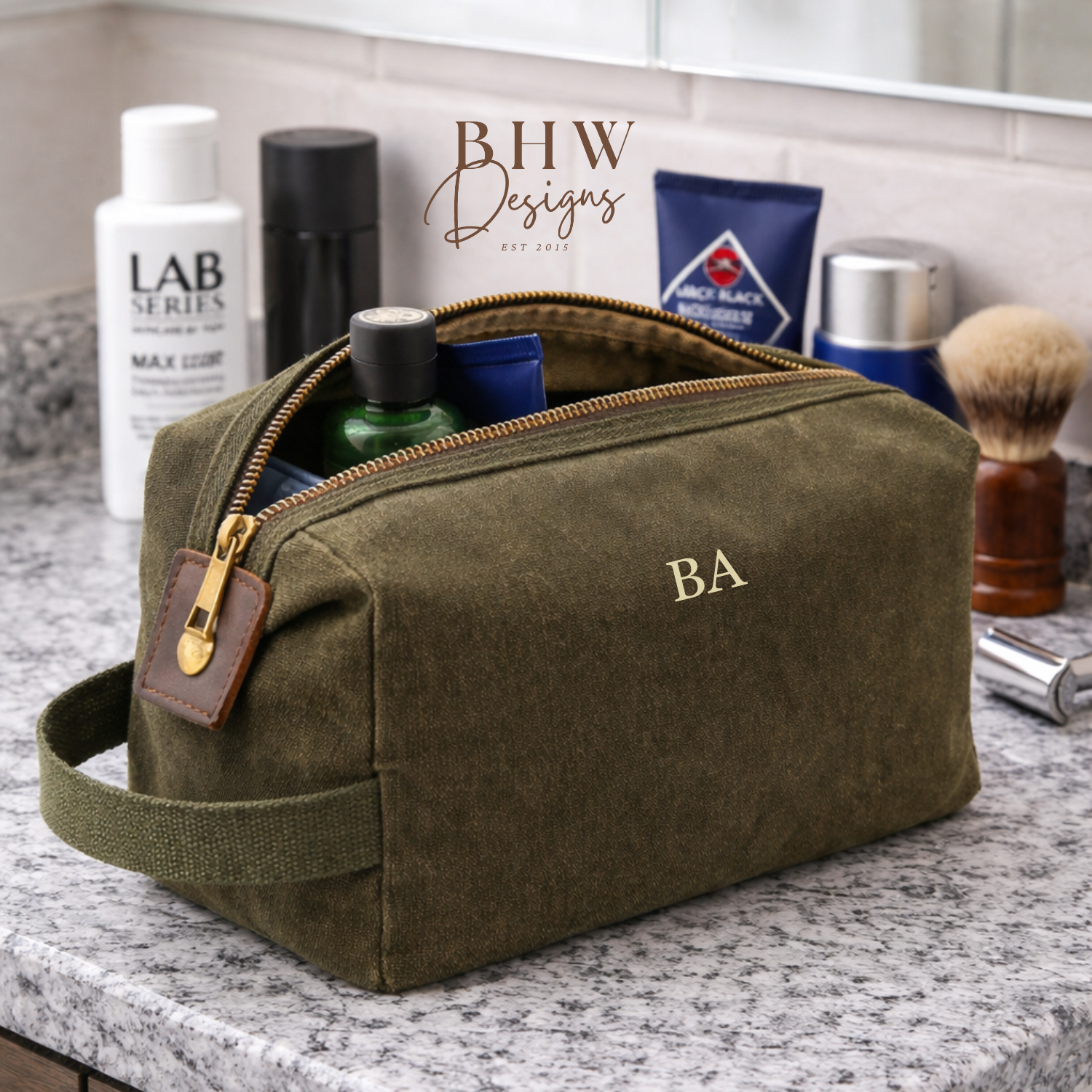 Olive green toiletry bag with 'BA' initials on a bathroom counter with grooming products.
