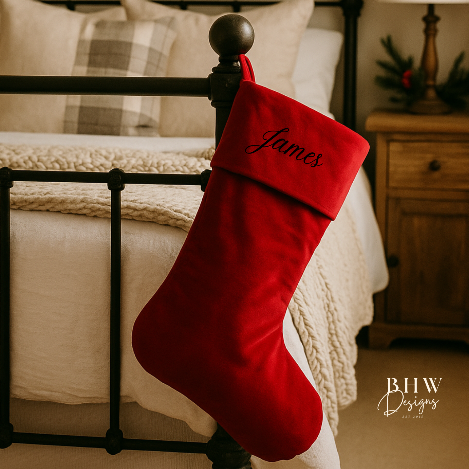 Red Christmas stocking with 'James' personalised on it, hanging on a bed post.