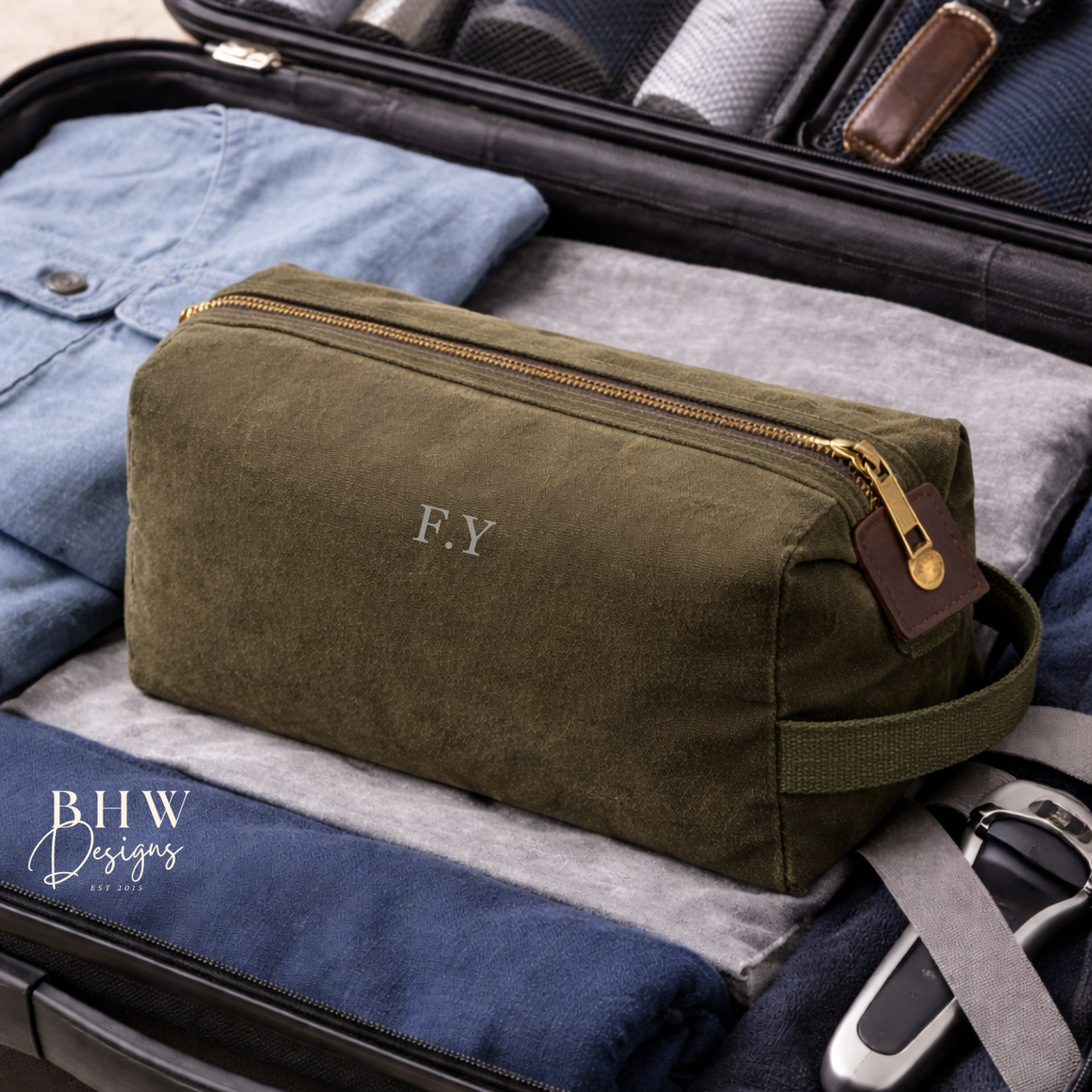 Green toiletry bag with initials in an open suitcase with travel items.