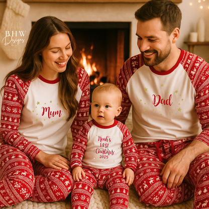 Family of three wearing matching red and white fair isle pyjamas in front of a fireplace.