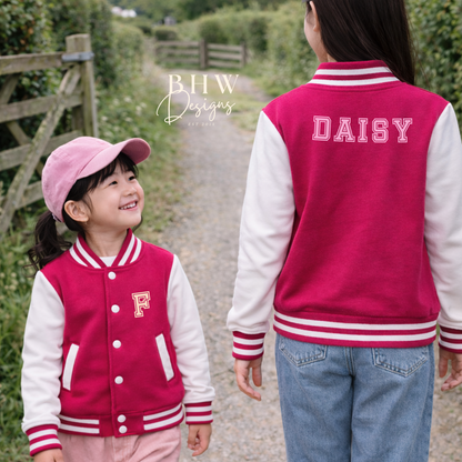 Two children wearing matching pink and white letterman jackets with 'DAISY' and 'F' on a path.