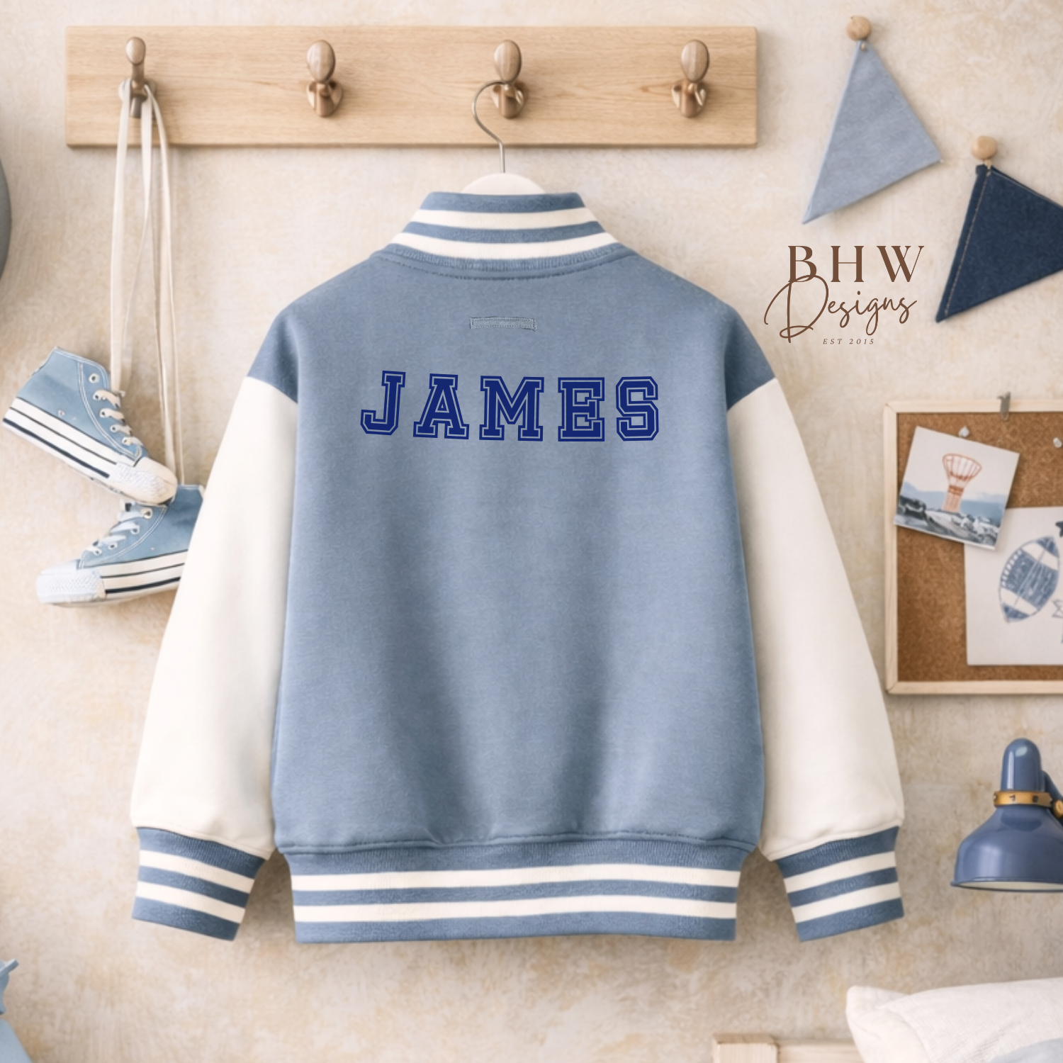 Dusky blue and white varsity jacket with 'JAMES' on the back, hanging on a wooden coat rack.