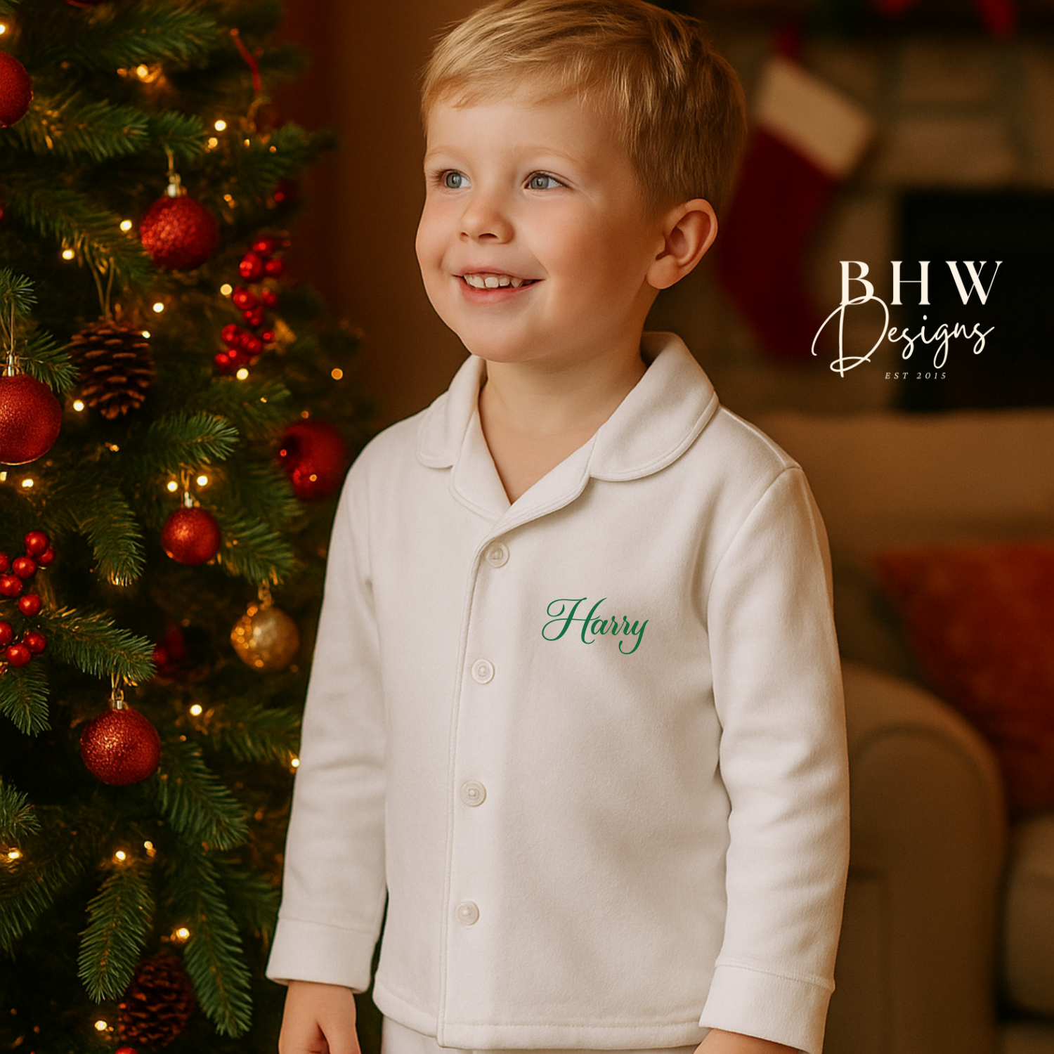 Child in a white pyjamas with 'Harry' printed on the chest, standing in front of a decorated Christmas tree.