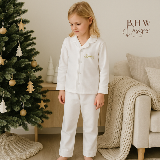 Child wearing white pajamas standing in a cozy living room with a decorated Christmas tree.